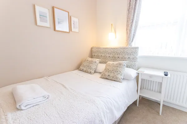 Single bed lit by natural light from a large window